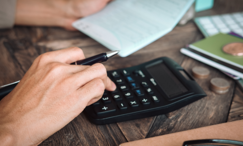 Empresário de restaurante concentrado analisando finanças com calculadora e documentos sobre a mesa, planejando a renegociação de dívida ativa para redução de custos.